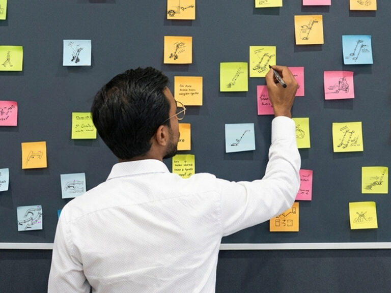 un homme dessine sur des post it pour une phase d'innovation produit